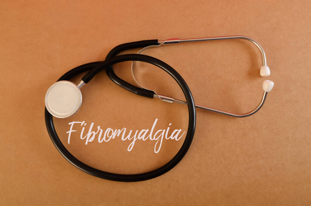 Stethoscope with text Fibromyalgia. Fibromyalgia is a chronic disorder pain throughout the body, other symptoms such as fatigue, muscle stiffness, sleep disturbances, and cognitive difficulties